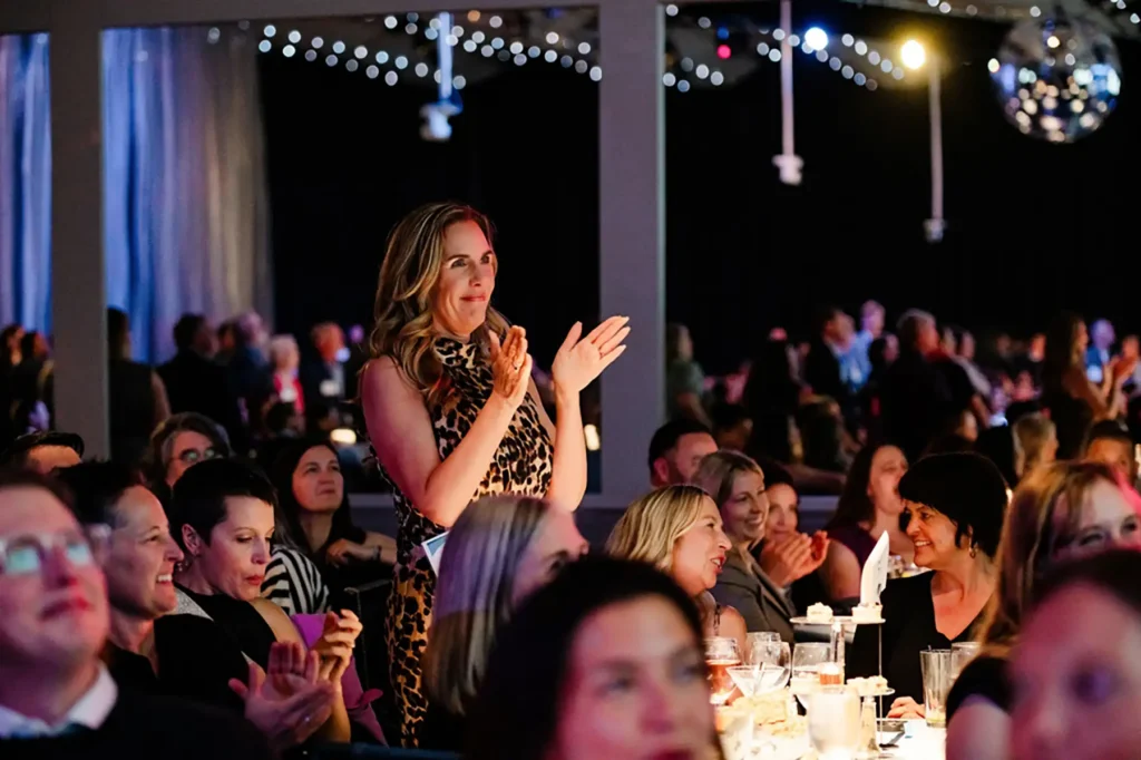 A woman stands up and claps at the Eagle Awards