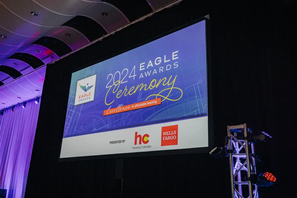 A projector screen showing a slide that says 2024 Eagle Awards Ceremony. Excellence in affordable housing. Presented by Housing Colorado and Wells Fargo