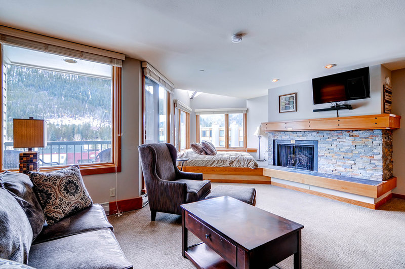 A small sitting room with a table, couch and chairs in front of a fireplace
